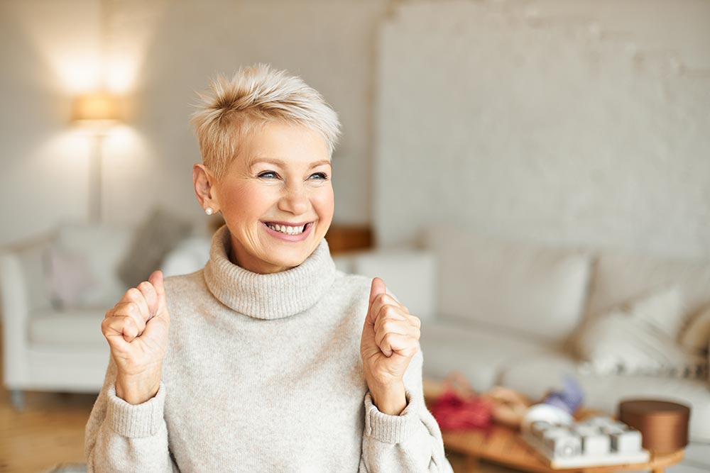 Femme d'environ 60 ans, souriante et rayonnante, illustrant l’épanouissement et le bien-être,
