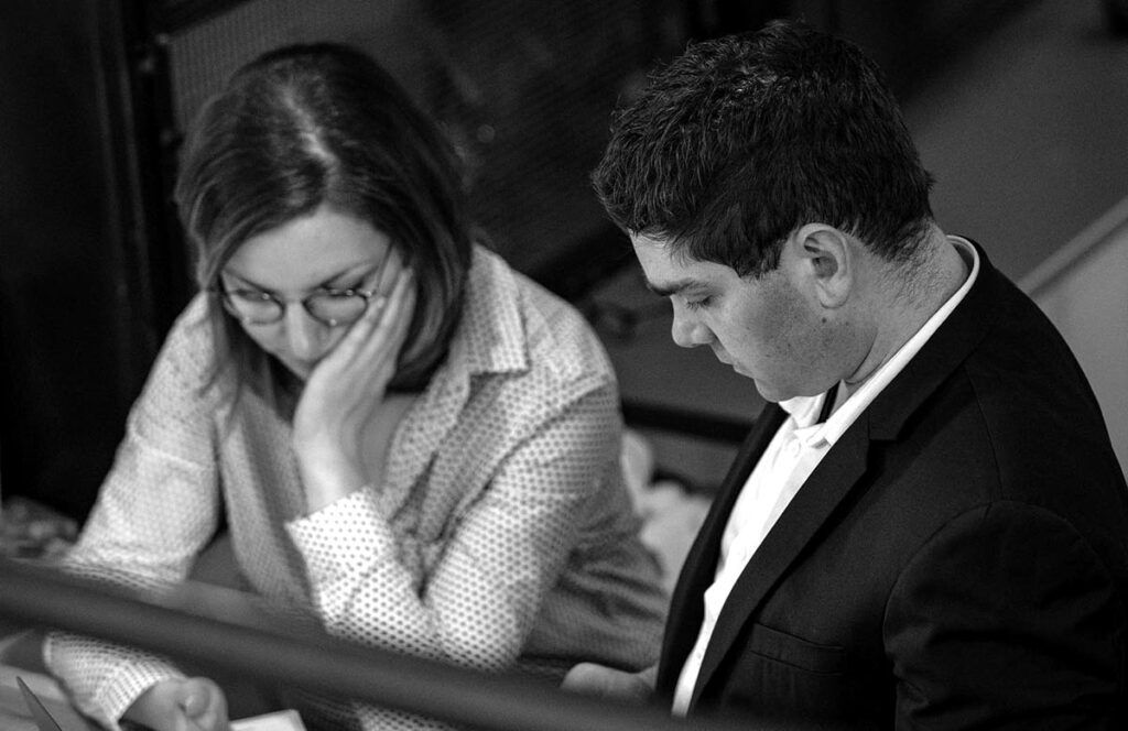 Sabrina et Nicolas, soucieux et inquiets regardant leurs comptes bancaires sur leurs portables. Leur situation difficile les a rendus plus résilients et déterminés à rebondir.