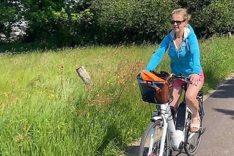 Je roule heureuse avec un grand sourire et des lunettes de soleil sur une petite route de campagne, les cheveux au vent et le cœur léger.