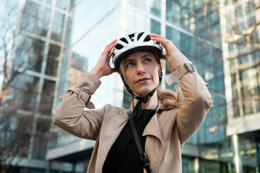 Une jeune femme mettant son casque de vélo avant de reprendre la route vers son travail.