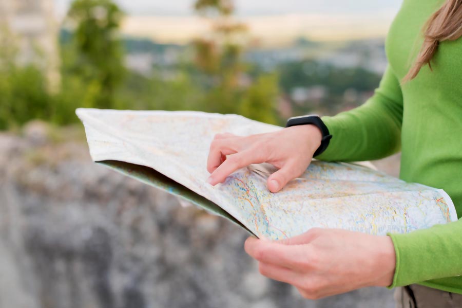 Les mains d'une femme étudiant son itinéraire sur une carte routière avant de prendre la route à vélo.