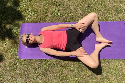 Béa, la fondatrice de Femme en Harmonie, fait des exercices d'étirements dans son jardin en tenue de sport