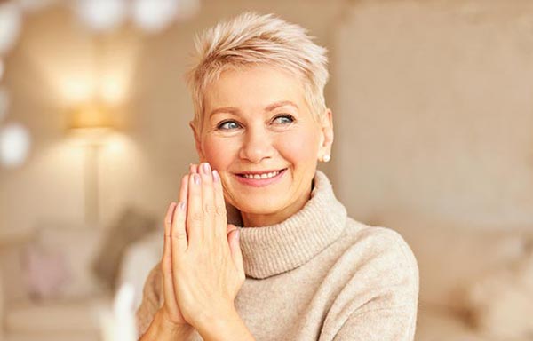 Femme blonde aux cheveux courts, souriante, illustrant l'idée d'un esprit frais et réceptif pour débuter sa journée.