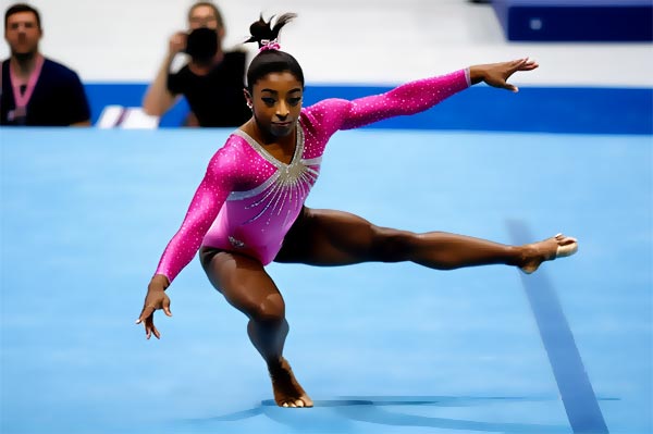 La jeune gymnaste en justaucorps rose fluo exécutant un mouvement de gymnastique au sol pendant les Championnats du monde de gymnastique artistique en 2013.