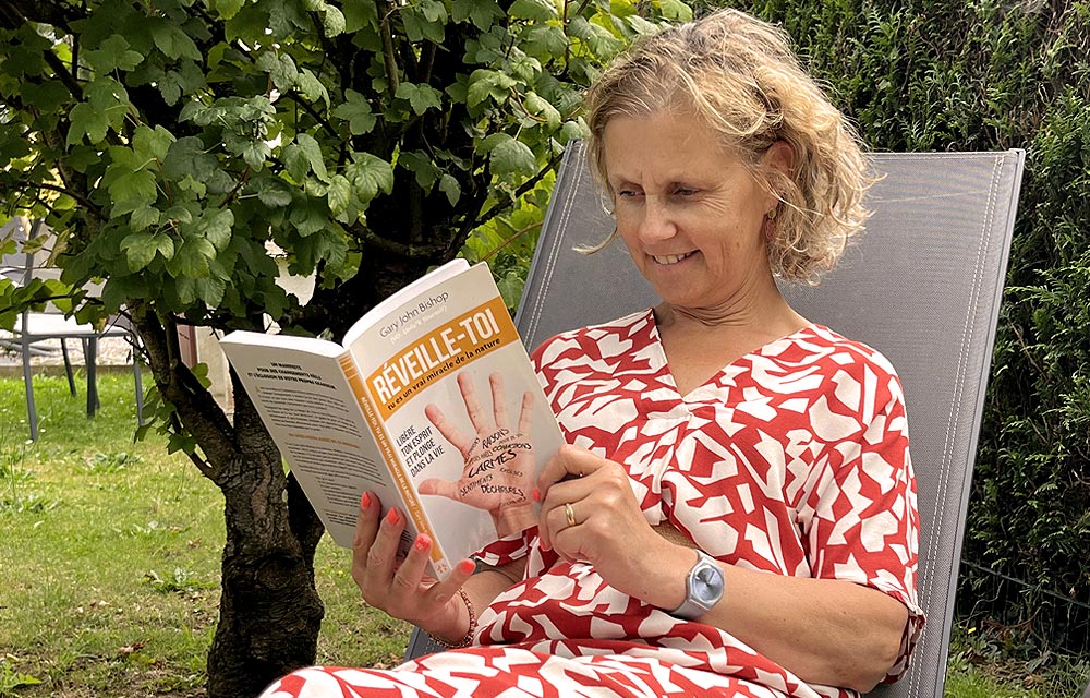 Je lis un livre sur la confiance en soi en me relaxant sur un bain de soleil dans mon jardin.
