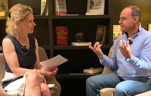 Béa et Philippe explorent les raisons pour lesquelles l’ostéopathie peut être essentielle après 45 ans, notamment pour soulager les tensions dues aux fluctuations hormonales, dans le salon cosy d'un bel hôtel.