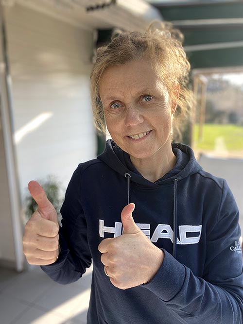 Béa, la créatrice de Femmes en Harmonie, souriante portant un sweat-shirt bleu marine à capuche, les deux pouces en avant, illustrant l'encouragement à maîtriser les symptômes de la ménopause avec des solutions naturelles.