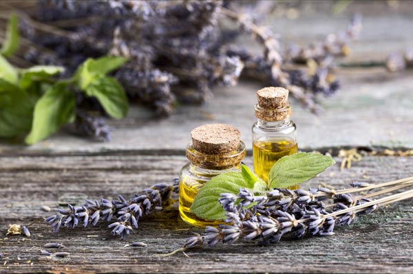 Fioles d'huile essentielle de lavande sur une table rustique en bois, entourées de brins de lavande, illustrant les bienfaits des huiles essentielles pour la relaxation.