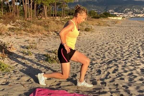 Béa exécute des fentes avant sur une plage, renforçant les muscles de ses jambes et de ses fessiers.