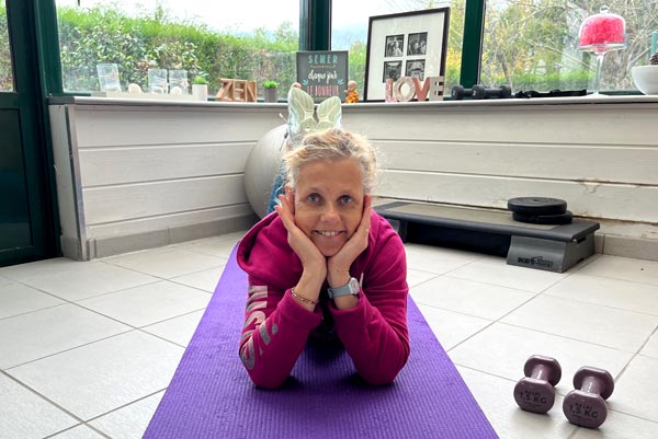 Béa, fondatrice de Femmes en Harmonie, allongée sur un tapis de yoga à la maison, illustre l’importance des exercices ciblés pour brûler des calories après 45 ans.