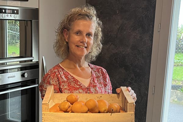 Béa, créatrice de Femmes en Harmonie, tenant un cageot de poires fraîchement récoltées dans son jardin. Cette image illustre l'importance des ingrédients de saison dans la création de plats réconfortants, sains et nourrissants, en mettant l'accent sur le bien-être et la convivialité.