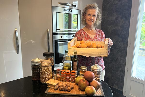Béa, créatrice de Femmes en Harmonie, dans sa cuisine entourée d'ingrédients sains et nutritifs pour des plats réconfortants. Cette image évoque l'importance d'une alimentation équilibrée, mettant en avant des légumes de saison, des protéines maigres et des graisses saines.