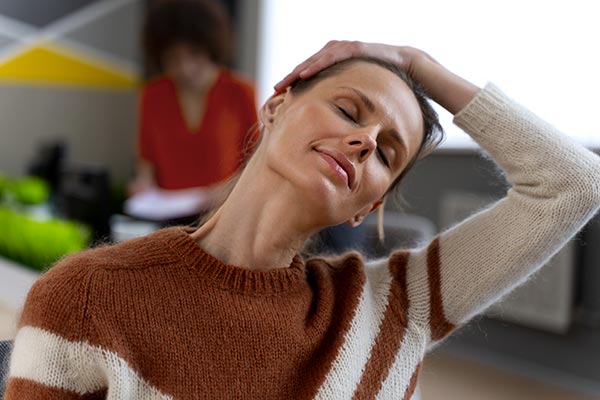 Femme pratiquant des étirements du cou en position de relaxation, illustrant l'importance de la relaxation régulière pour réduire le stress et mieux gérer son poids en évitant les effets du cortisol.