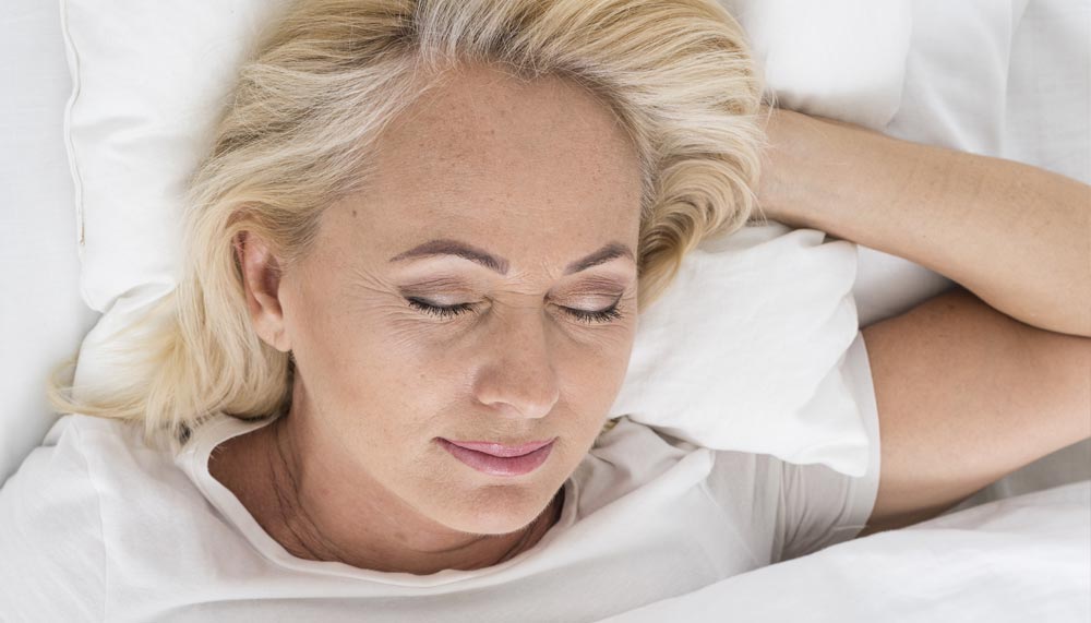 Femme dormant paisiblement, illustrant l'importance d'adopter un horaire de sommeil régulier et de veiller à la qualité du repos pour mieux gérer le poids avec l'âge.