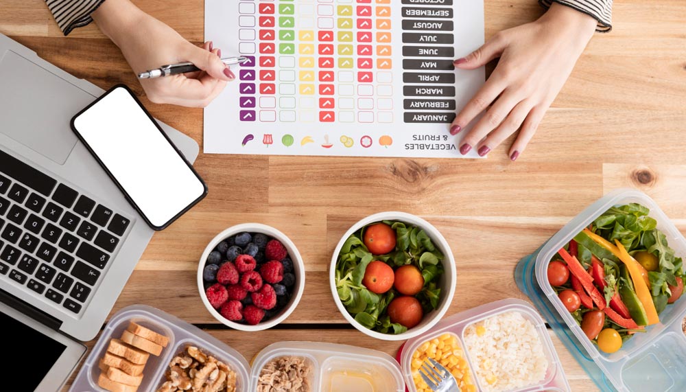 Mains d'une femme devant différents aliments faisant calcul des