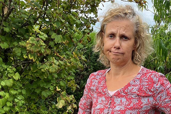 Béa, fondatrice de Femmes en Harmonie, dans son jardin, portant un chemisier fleuri et faisant la grimace, pour illustrer l’importance de retrouver la motivation face aux épreuves du quotidien après 45 ans.