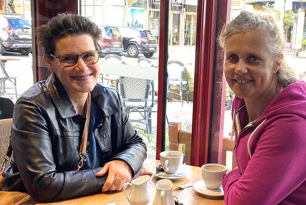 Béa, la fondatrice de Femmes en Harmonie, et Sandra, souriantes, échangeant un moment ensemble dans un café. Le sujet évoqué : L'importance du soutien et de la résilience face au syndrome du nid vide et aux défis émotionnels.