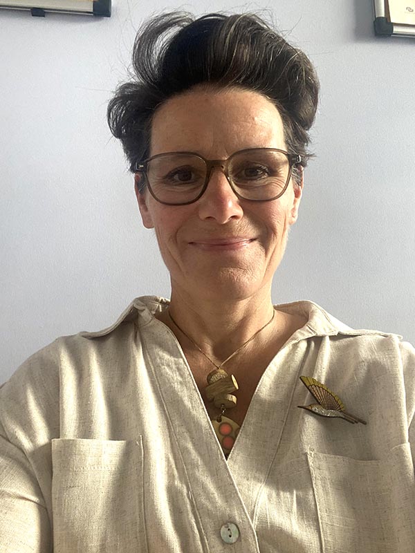 Sandra avec un magnifique sourire devant un fond lumineux, symbolisant la résilience et la transformation personnelle après avoir vécu le syndrome du nid vide.