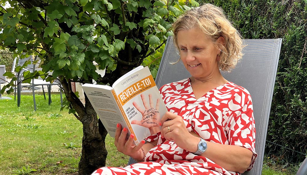 Béa se relaxant avec un livre dans le jardin. Illustration des bienfaits de la lecture pour réduire le stress et favoriser la détente.