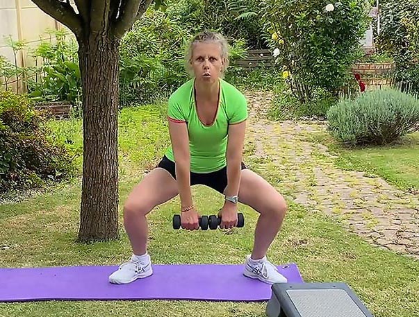 Béa, fondatrice de Femmes en Harmonie, réalise un exercice de musculation avec haltères dans son jardin. Illustration des bienfaits de la musculation pour les femmes, tels que la force, l’équilibre, et la vitalité après 45 ans.