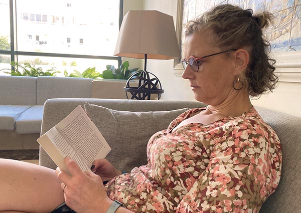 Béa, fondatrice de Femmes en Harmonie, assise confortablement en train de lire, illustrant les bienfaits de la lecture pour l'esprit et le bien-être.
