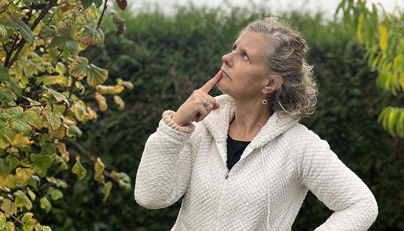Béa, pensive dans son jardin, sur l'idée de transformer cette étape de la vie en une opportunité de redécouverte d'elle-même et de bien-être personnel.