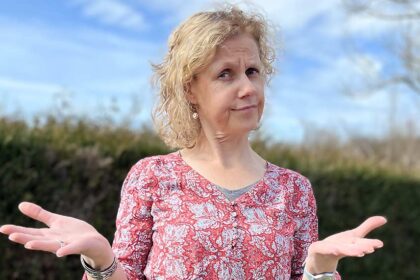 Béa, 55 ans, la fondatrice de Femmes en Harmonie, dans son jardin, perplexe devant la prise de poids à la ménopause. Elle exprime ses interrogations face aux changements hormonaux, à l’accumulation de graisse abdominale et aux difficultés à stabiliser son poids.