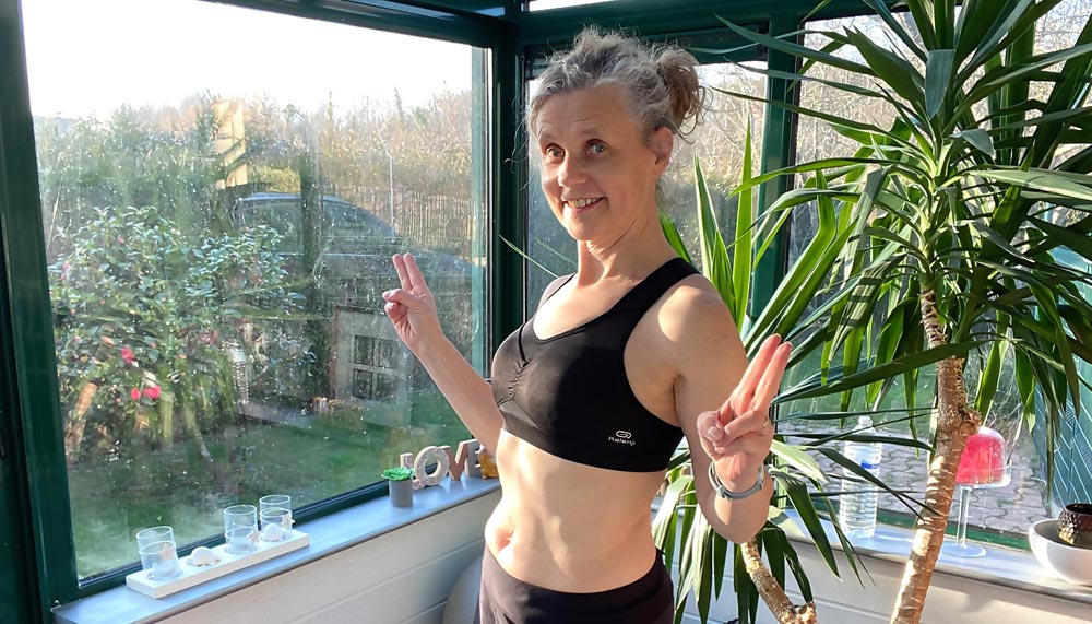 Béa, fondatrice de Femmes en Harmonie, démontre les bienfaits d’une routine douce d’exercices pour obtenir un ventre plat après 50 ans, sans crunchs ni pression sur le périnée, dans l'ambiance bienveillante et lumineuse de sa véranda.
