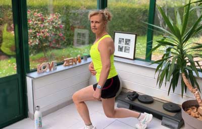 Béa effectue une fente classique dans une pièce lumineuse. Cet exercice sollicite les fessiers, les quadriceps et les muscles profonds, favorisant une meilleure coordination, une tonification du bas du corps, et une activation du métabolisme sans impact sur les articulations.